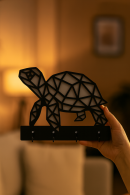 Handheld black MDF wall hanger with modern turtle silhouette, four hook keys and accessory hanging bracket
